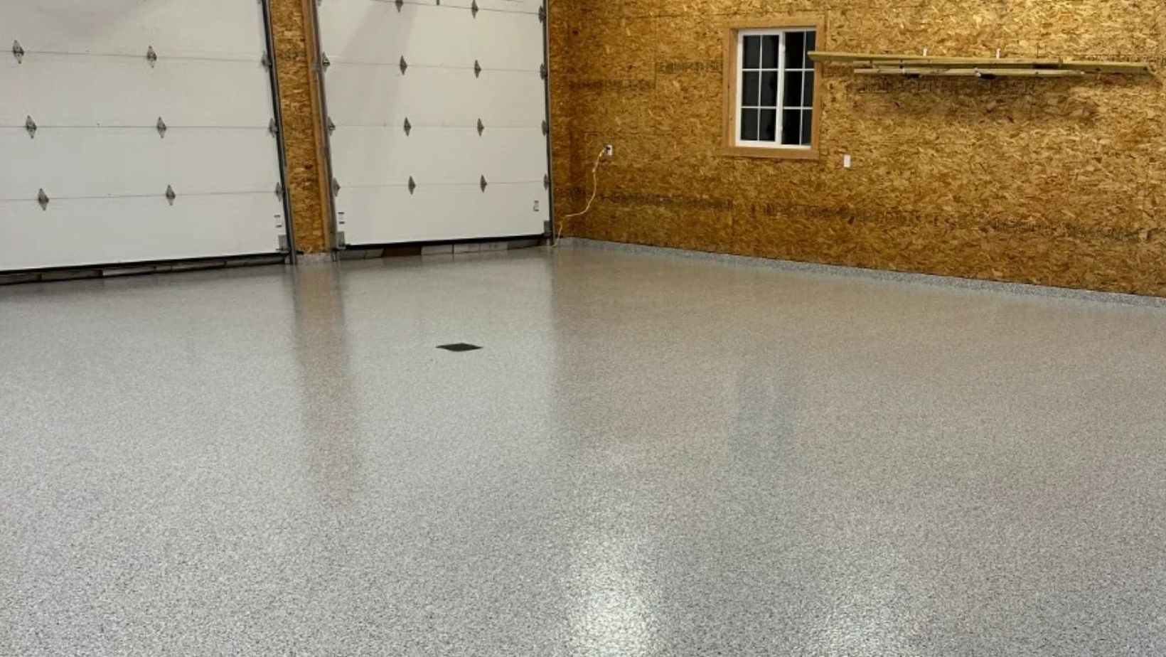 Pole-barn garage with white overhead doors finished with a grey speckled flake floor coating