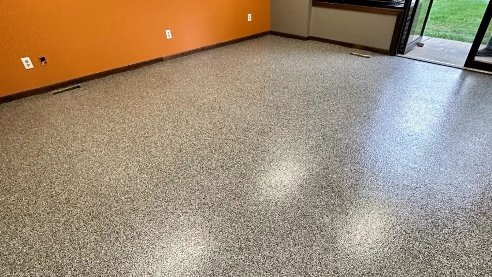 Room with an orange accent wall finished with a tan speckled flake floor coating